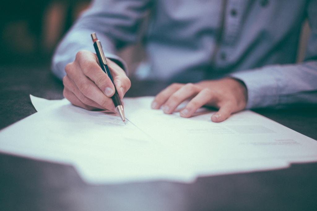 A person writing a holographic will by hand on paper at a desk