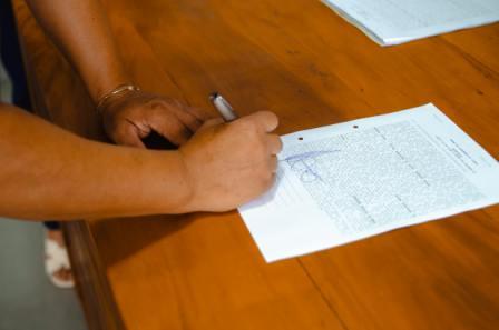 Person signing a legal will document in Alberta at a wooden desk